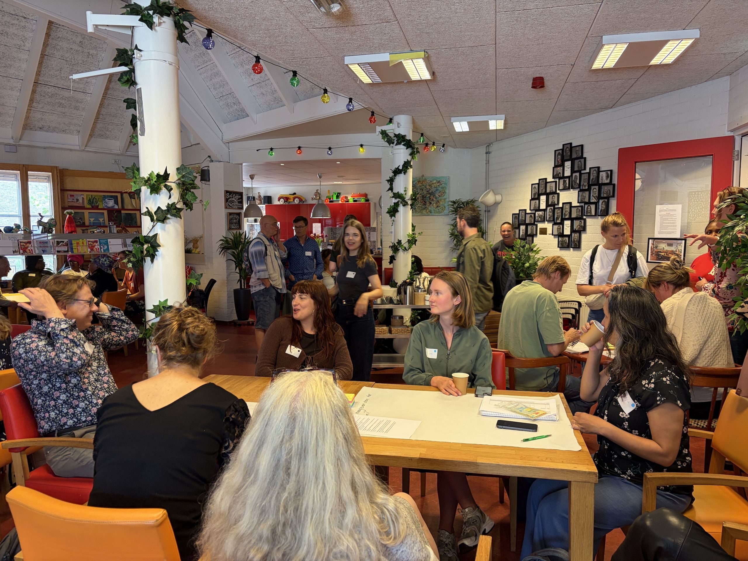 De zaal met aanwezigen aan het werk aan tafel